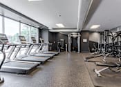 Thumbnail 15 of 25 - A gym with treadmills and weight machines.