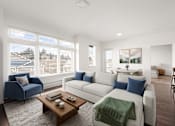 Thumbnail 3 of 26 - A living room with a blue chair, a white couch, and a coffee table.