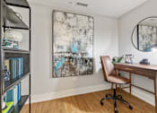 Thumbnail 13 of 27 - A room with a desk, chair, and a painting on the wall.