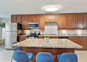 Thumbnail 6 of 27 - A kitchen with a granite countertop and blue chairs.