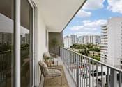 Thumbnail 10 of 31 - A balcony with a table and chairs overlooks a cityscape.