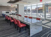Thumbnail 23 of 31 - Co-working area at 3thirty3 New Rochelle NY high-rise, featuring a marble community table, modern furniture, and window wall with city skyline view.