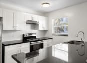 Thumbnail 1 of 12 - a kitchen with white cabinets and black counter tops