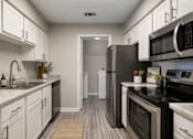 Thumbnail 1 of 13 - Rutland Place Apartment Homes in Macon, Georgia with A modern kitchen with white cabinets and stainless steel appliances.