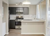 Thumbnail 1 of 18 - Tempe, AZ Apartments – Sentry Tempe – a white kitchen with black cabinets and a microwave