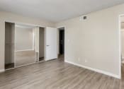 Thumbnail 8 of 18 - Pet-Friendly Apartments in Tempe – Sentry Tempe – an empty living room with wood flooring and a mirrored closet