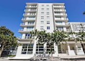 Thumbnail 25 of 27 - Pet-Friendly Rentals in Miami River, FL – Riverview One Apartments – A photo of our exterior of the building with trees in front