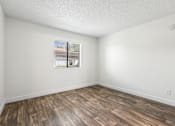 Thumbnail 26 of 46 - A room with wooden flooring and a window showing a view of a building.