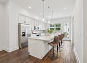 Thumbnail 2 of 39 - A modern kitchen with a refrigerator, sink, and bar stools.