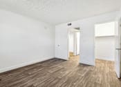 Thumbnail 27 of 46 - A room with white walls and wood flooring with a doorway leading to another room.