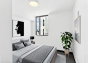 Thumbnail 3 of 9 - A bedroom with a bed, a potted plant, and pictures on the wall.