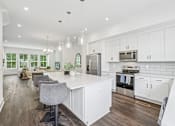 Thumbnail 3 of 39 - A modern kitchen with white cabinets and a central island.