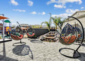 Thumbnail 12 of 25 - Four hanging chairs are placed on a patio.