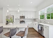 Thumbnail 1 of 39 - A kitchen with white cabinets and a large island with chairs.