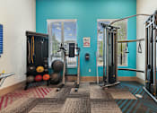 Thumbnail 7 of 28 - A gym with a blue wall and a variety of exercise equipment.