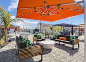 Thumbnail 14 of 25 - A patio with a table, chairs and an orange umbrella.