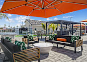 Thumbnail 10 of 25 - A patio with a table, chairs and a bench under an orange umbrella.