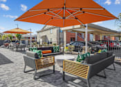 Thumbnail 2 of 25 - Two chairs and a table are under an orange umbrella.