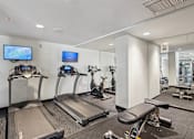 Thumbnail 16 of 27 - Apartments for Rent in Riverview Miami, FL– Riverview One Apartments -   A gym with treadmills, exercise bikes, and a television.