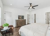 Thumbnail 13 of 39 - A bedroom with a large bed, a dresser, and a ceiling fan.