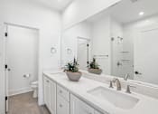 Thumbnail 15 of 39 - A white bathroom with a sink, mirror, and potted plants.