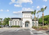 Thumbnail 2 of 28 - A white building with a black roof and palm trees in front.