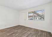 Thumbnail 23 of 46 - A room with a wooden floor and a window showing a building outside.