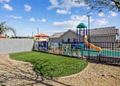 Thumbnail 5 of 25 - A playground with a green slide and a mural on the wall.