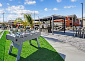 Thumbnail 15 of 25 - A foosball table is in the middle of a grassy area.