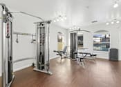 Thumbnail 18 of 19 - Affordable Apartments in Austin, TX for Rent- Huntington Meadows-  A gym with a variety of equipment including a squat rack, bench, and weights.