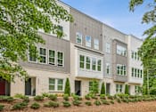 Thumbnail 32 of 39 - A modern building with a grey facade and white trim is surrounded by greenery.