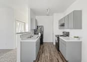 Thumbnail 12 of 19 - Affordable Apartments in Austin, TX for Rent- Huntington Meadows-  A kitchen with a white counter top and grey cabinets.