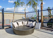 Thumbnail 19 of 25 - A black metal fence surrounds a circular wicker sofa.