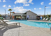 Thumbnail 20 of 25 - A pool with sun loungers and a building in the background.