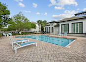 Thumbnail 5 of 28 - A pool with a blue tiled edge and a white sunbed.