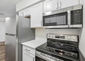 Thumbnail 18 of 46 - A modern kitchen with a stainless steel refrigerator, microwave, and oven.