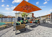Thumbnail 23 of 25 - A patio with a table and chairs under an orange umbrella.