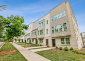 Thumbnail 28 of 39 - A modern apartment building with a tree-lined sidewalk in front.