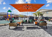 Thumbnail 24 of 25 - A patio with a large umbrella and a table with chairs.