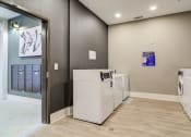 Thumbnail 8 of 19 - Sky Harbor Apartments in Chamblee, GA photo of a a laundry room with washers and dryers and a door to a closet