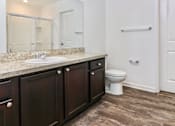Thumbnail 32 of 75 - A white toilet sits in a bathroom with dark wood cabinets.