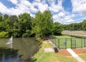 Thumbnail 14 of 15 - a tennis court overlooking a pond with a fountain