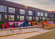 Thumbnail 16 of 29 - A modern building with colorful doors and windows.