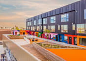 Thumbnail 14 of 29 - A modern building with colorful exterior walls and a wooden deck in front.