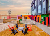 Thumbnail 15 of 29 - A colorful building with a patio and chairs.