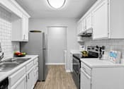 Thumbnail 1 of 18 - Modern kitchen with white cabinetry and stainless steel appliances at Southwinds Point Apartments in Stockbridge, Georgia.