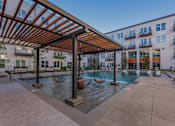 Thumbnail 11 of 28 - Pet-Friendly Apartments in Downtown Dallas, TX- 4600 Ross- Sparkling Pool with Swinging Chairs and Poolside Couches