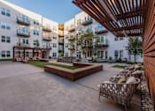 Thumbnail 24 of 28 - Apartments for Rent in Downtown Dallas, TX - 4600 Ross - Modern Courtyard with Comfortable Seating Options, a Grilling Station, and Beautiful Landscaping