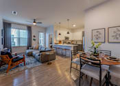 Thumbnail 7 of 28 - a living and dining area with a table and chairs and a kitchen in the background