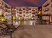 Thumbnail 27 of 28 - Old East Dallas, TX Apartments - 4600 Ross - Oversized Pool with Boho-Inspired Wet Deck, Swings, Cascades, Submerged and Poolside Lounge Seats, and Lighted Trees.